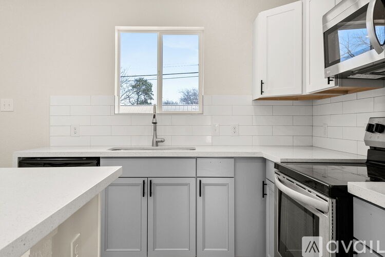 A kitchen with white cabinets and a window overlooking a tree.