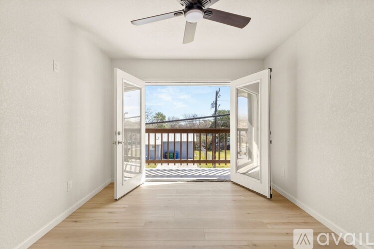 A room with a ceiling fan and a door leading to a balcony.