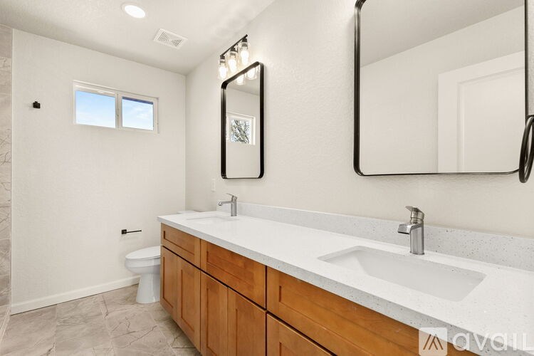 A bathroom with a toilet, sink, and mirror.