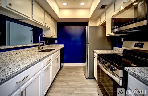 A kitchen with white cabinets and a blue wall.