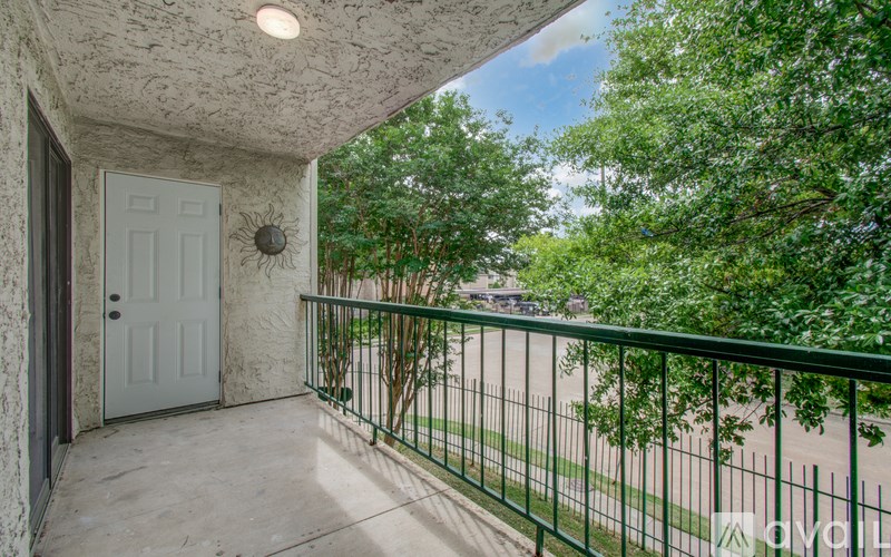 A balcony with a white door and a green railing.