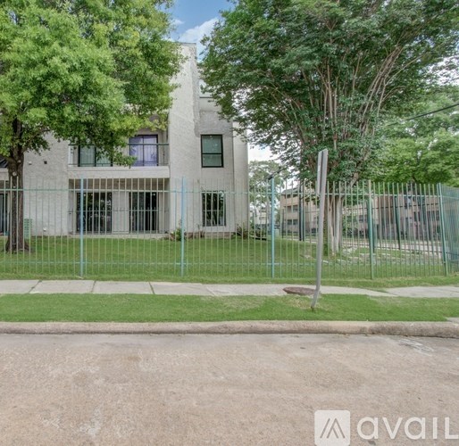 A modern building with a fence and trees in front.