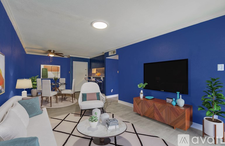 A living room with a white sofa, a wooden coffee table, and a flat screen TV mounted on the wall.