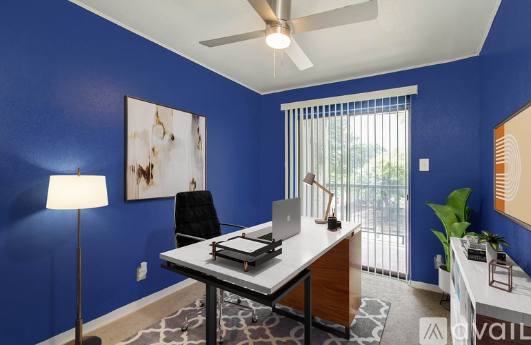 A room with blue walls and a desk with a laptop and a lamp.