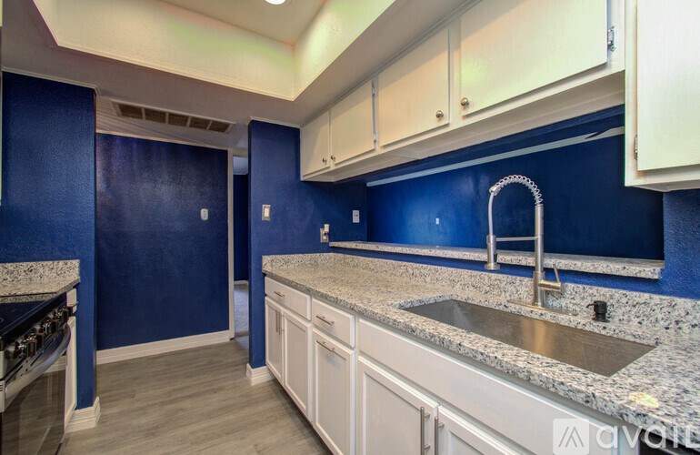 A kitchen with blue walls and white cabinets.