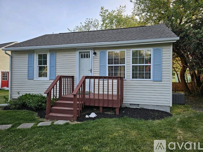 A small house with a blue door and a wooden porch.