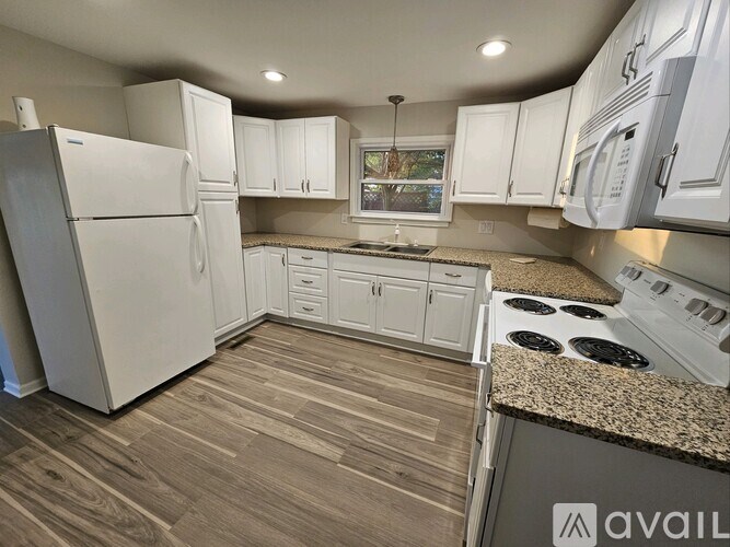A kitchen with white appliances and wooden floors.
