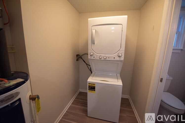 A small white washing machine in a narrow room.
