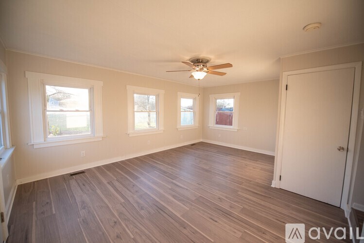A room with a ceiling fan and three windows.