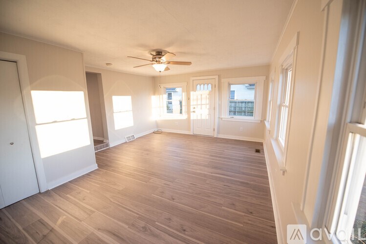 A spacious room with wooden floors and a ceiling fan.
