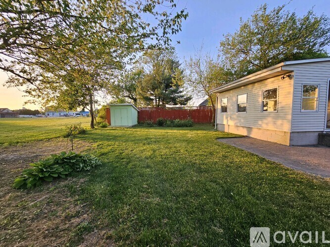 A house with a green shed and a tree in the foreground.