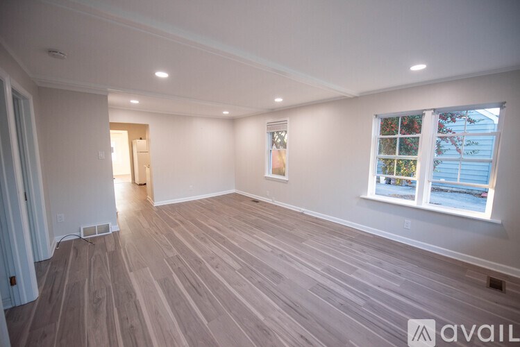 A room with wooden flooring and a window showing a view of a body of water.