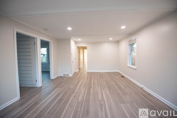 A spacious room with wooden flooring and white walls.