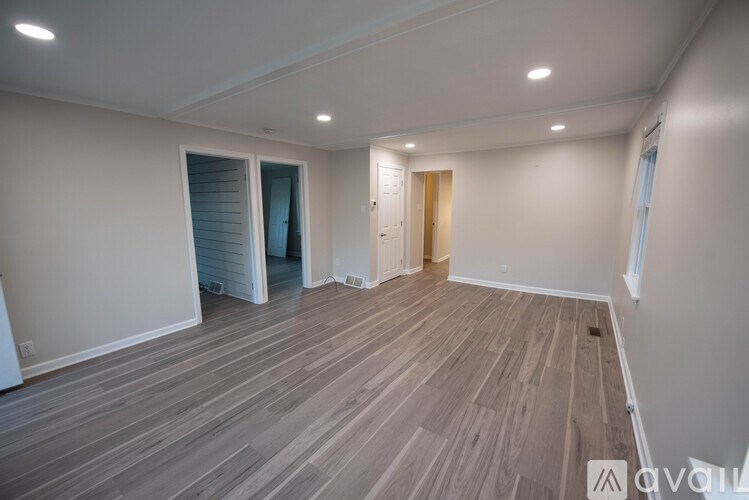 A room with wooden flooring and a door leading to another room.