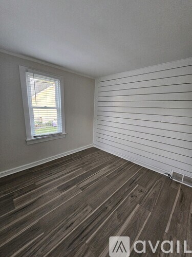 A room with wooden flooring and a window with blinds.