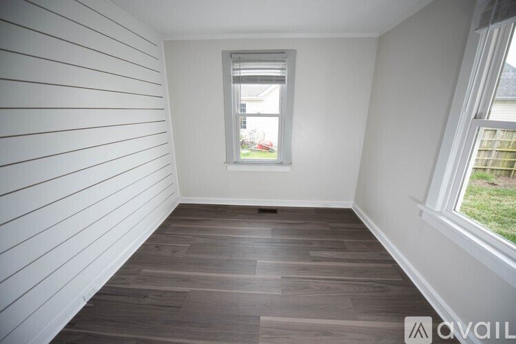 A room with wooden flooring and white walls.
