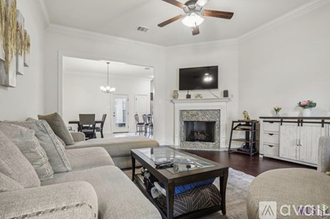 A living room with a grey sofa, a coffee table, and a television above the fireplace.