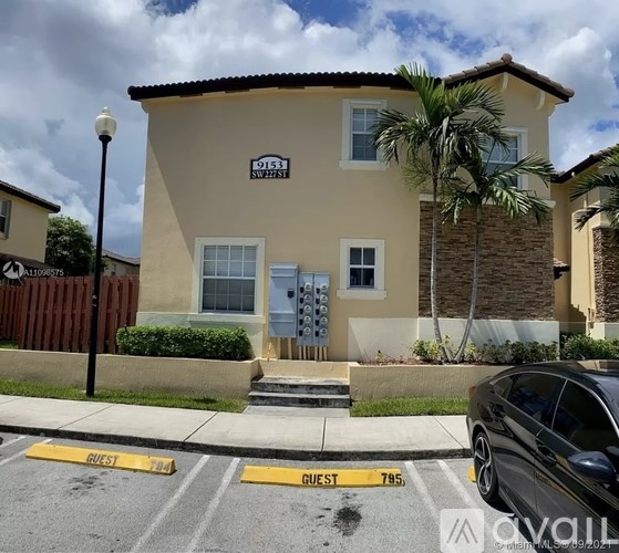 A beige house with a black car parked in front.