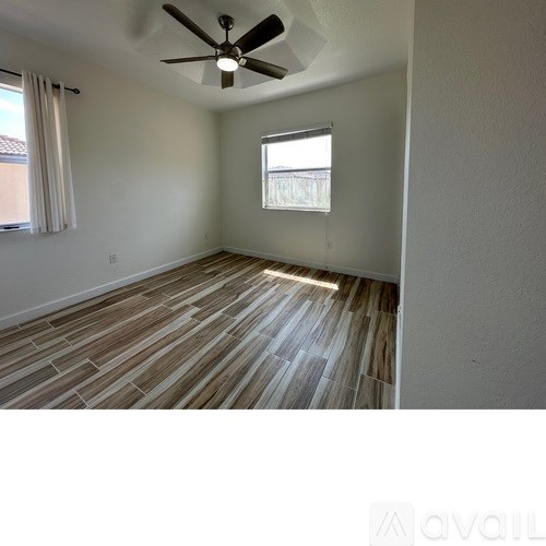 A room with a ceiling fan and a window with blinds.