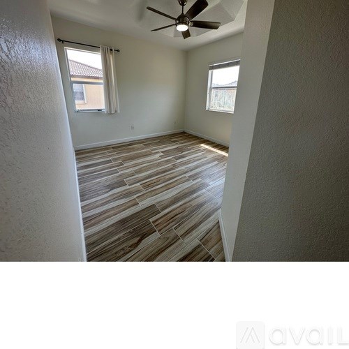 A room with a ceiling fan and wood flooring.