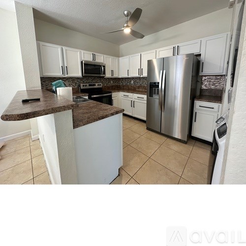 A kitchen with a refrigerator, microwave, and oven.