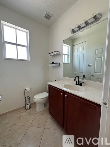 A bathroom with a toilet, sink, and mirror.