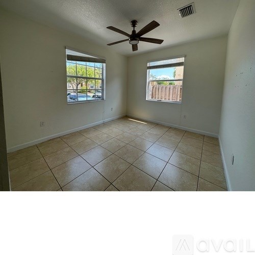 A room with a ceiling fan and two windows.