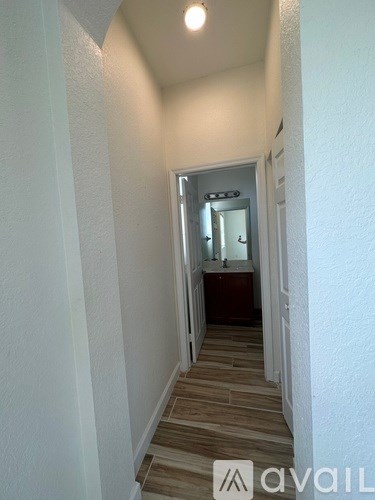A hallway with a mirror and a door at the end.