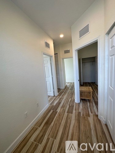 A hallway with wooden flooring and white walls.