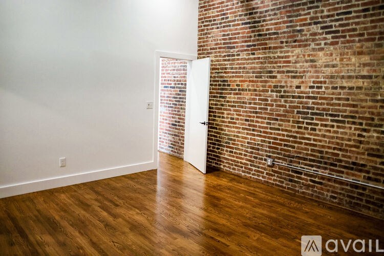 A room with a white door and a brick wall.