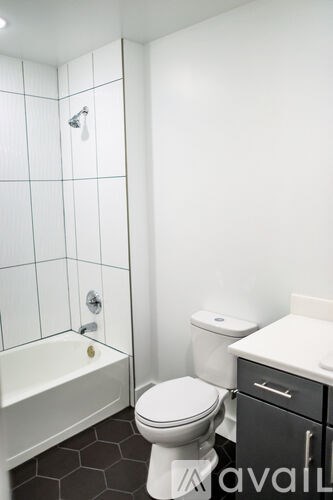 A white toilet sits next to a white bathtub in a small bathroom.