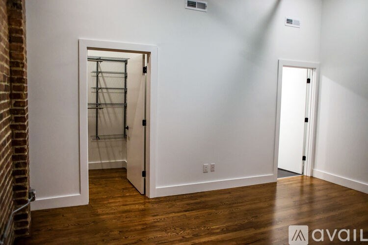 A room with a white door and a brick wall.