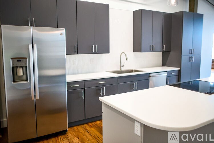 A modern kitchen with a stainless steel refrigerator and dark grey cabinets.