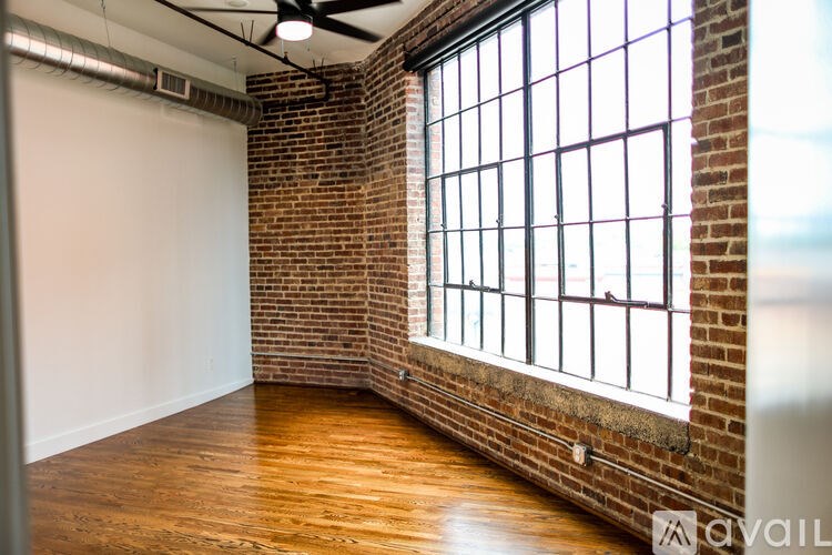 A room with a large window and a brick wall.