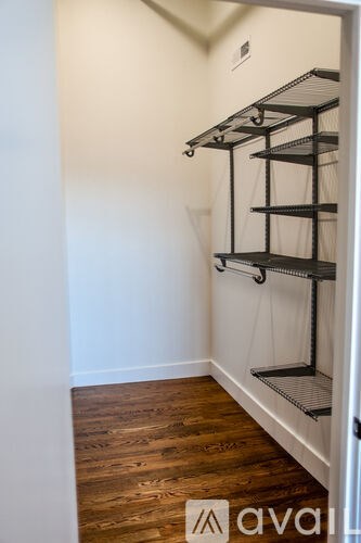 A white closet with a black shelving unit and wooden floors.