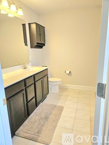 A bathroom with a toilet, sink, and cabinet.