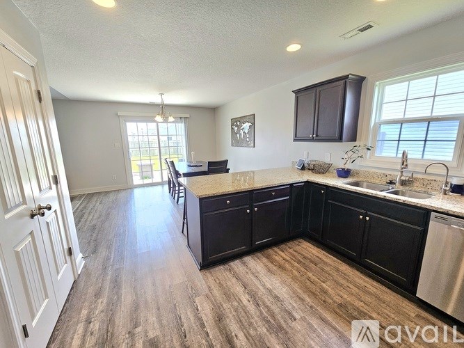 A kitchen with black cabinets and a wooden floor.