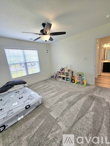 A bedroom with a bed, a ceiling fan, and a window with blinds.