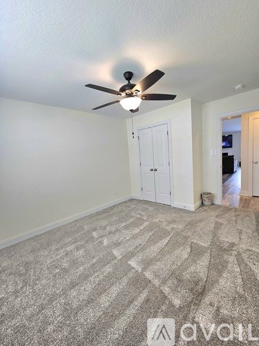 A room with a ceiling fan and carpeted floor.