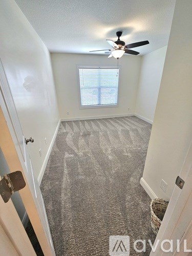 A room with a ceiling fan and a window with blinds.