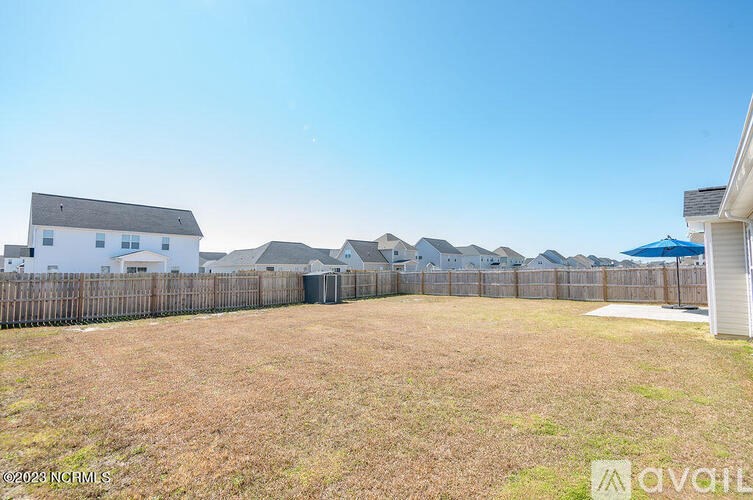 A backyard with a fence and a house in the background.