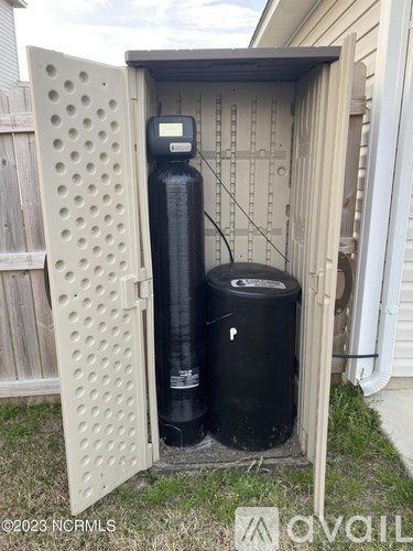 A black water heater and a black tank are in a shed.