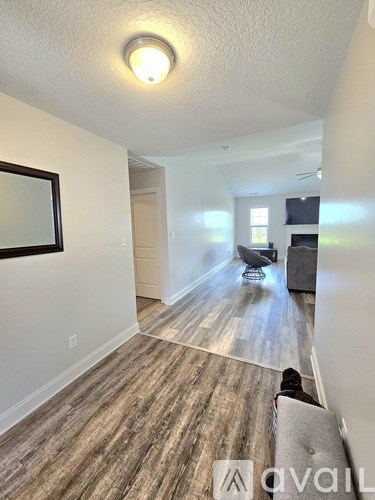 A long hallway with wood flooring and a mirror on the wall.