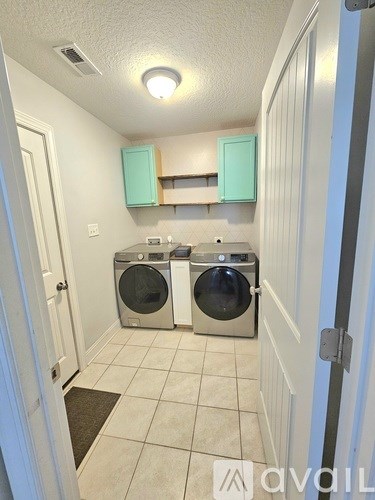 A laundry room with two washing machines and a cabinet above the counter.