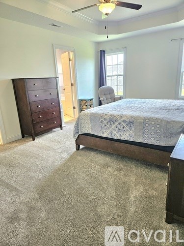 A bedroom with a bed, dresser, and chair.