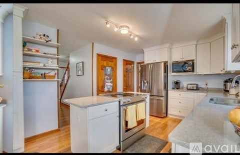 A kitchen with white cabinets and a stainless steel refrigerator.