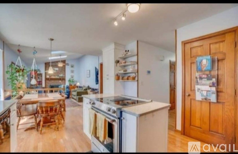 A kitchen with a wooden table and chairs, a stove, and a refrigerator.