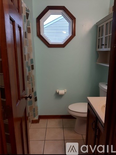 A bathroom with a toilet, a hexagonal mirror, and a tiled wall.