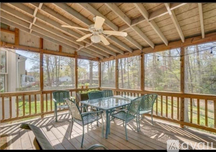 A screened porch with a table and chairs.