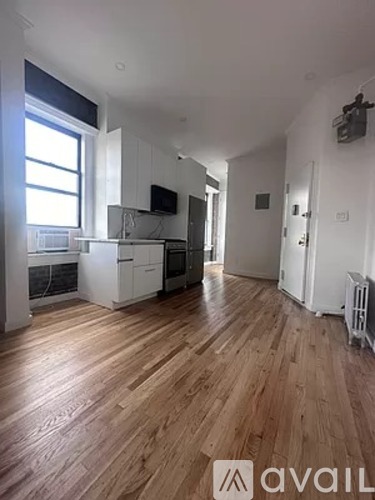 A spacious room with wooden flooring and white walls.